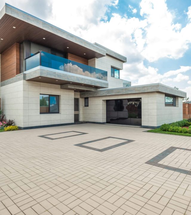pexels-photo-8134845-8134845 Elegant modern house exterior with lush greenery and ample driveway space.
